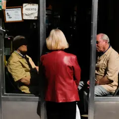 Una mujer de rojo observa a dos hombres dentro de una barbería. La composición sigue la regla de los tercios, creando una escena intrigante.
