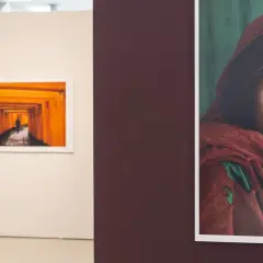 Una mujer observa una obra de Steve McCurry, destacando la icónica mirada de la niña afgana.