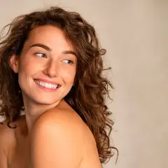 Mujer sonriente con pecas, cabello rizado y mirada radiante. Sigue la regla de la mirada para capturar su belleza natural.