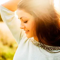 Momentos capturados en estas fotos pilladas: una joven sonríe con el sol en su rostro, su cabello suelto y un suéter adornado.