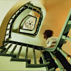 Vista en plano nadir de una escalera de caracol con una mujer mirando hacia arriba.