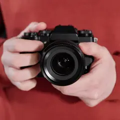 Manos sostienen una cámara negra, lista para el inicio fotografía.