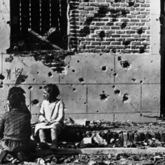 Niños juegan entre escombros frente a un edificio bombardeado, una escena conmovedora capturada en una de las robert capa fotos famosas.