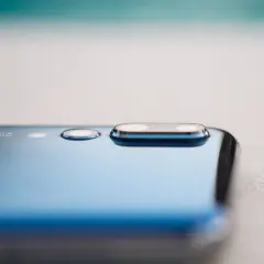 Detalle de la cámara de un smartphone azul, mostrando el módulo de lentes Leica y la tecnología de pixel binning para capturar más luz.