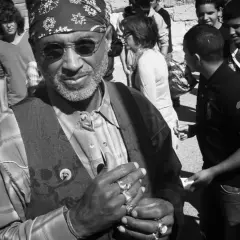 Stanley Greene, con su bandana y anillos, sonríe rodeado de jóvenes.