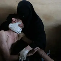 Una mujer con velo negro y guantes blancos consuela a un hombre herido. Foto de Samuel Aranda, World Press Photo.