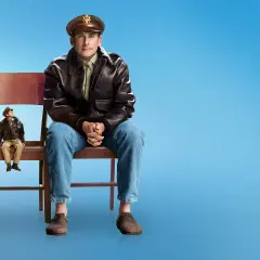 Mark Hogancamp, un hombre sentado en una silla, mira a su figura en miniatura en otra silla.