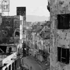 Calle devastada con edificios en ruinas, un cartel de "HOOVER" en lo alto. La mirada de Gabriele Basilico captura la desolación.