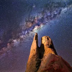 Rocas imponentes bajo la vía láctea en el cielo nocturno.
