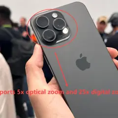 Mano sostiene un iPhone oscuro, mostrando su sistema de cámaras. El texto indica "zoom digital" de 25x y zoom óptico de 5x.