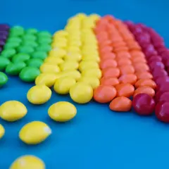 Caramelos de colores forman un arcoíris, demostrando la ley de contraste con sus vibrantes tonos sobre el fondo azul.