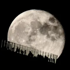 Siluetas de personas observan la luna llena desde una pasarela de cristal. Los parámetros de la foto de la luna capturan su textura y brillo.
