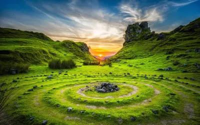 Paisaje verde con un círculo de piedras y un atardecer vibrante, capturado con técnica qué es HDR para resaltar detalles.