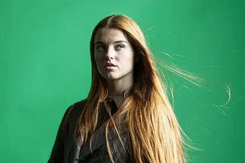 Mujer pelirroja con pecas, su cabello largo y suelto se mueve con el viento. La edición de **dodge and burn** resalta sus rasgos.