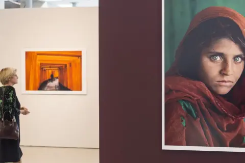Una mujer observa una obra de Steve McCurry, destacando la icónica mirada de la niña afgana.
