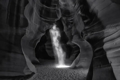 Columna de luz ilumina cañón de arena, creando una escena etérea. Esta podría ser la **fotografía más cara del mundo** por su belleza única.