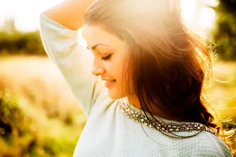 Momentos capturados en estas fotos pilladas: una joven sonríe con el sol en su rostro, su cabello suelto y un suéter adornado.