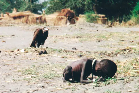 Un niño desnutrido y un buitre en un paisaje árido. Una imagen impactante que podría ser parte de fotos premiadas.
