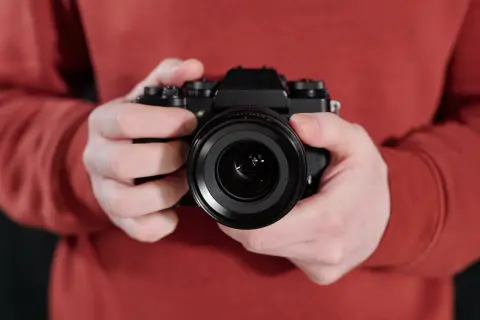Manos sostienen una cámara negra, lista para el inicio fotografía.