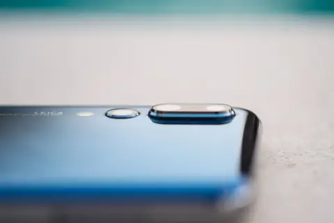 Detalle de la cámara de un smartphone azul, mostrando el módulo de lentes Leica y la tecnología de pixel binning para capturar más luz.