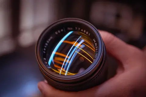 Primer plano de un objetivo de cámara vintage, reflejando luces de colores.