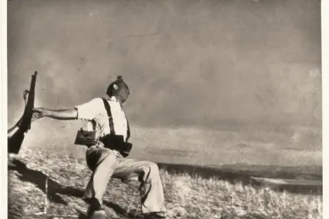 Soldado con rifle en mano, capturado en un momento dramático que evoca la muerte de Gerda Taro.