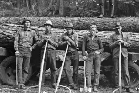 Cinco leñadores posan con sus herramientas junto a un tronco, capturados por Dorothea Lange.