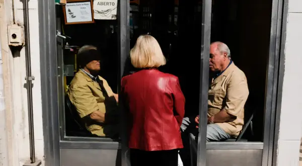 Una mujer de rojo observa a dos hombres dentro de una barbería. La composición sigue la regla de los tercios, creando una escena intrigante.