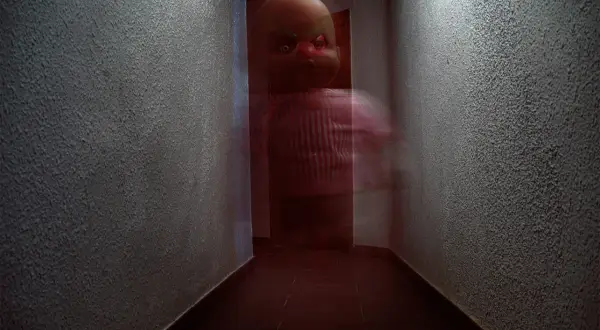 Un muñeco con ojos rojos y cejas verdes aparece en un pasillo oscuro. Son fotos que dan mucho miedo.