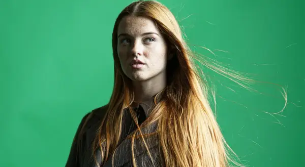 Mujer pelirroja con pecas, su cabello largo y suelto se mueve con el viento. La edición de **dodge and burn** resalta sus rasgos.