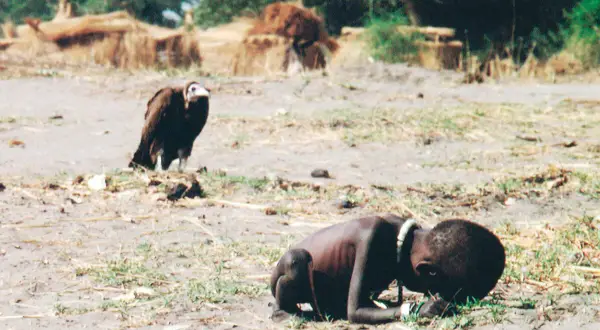 Un niño desnutrido y un buitre en un paisaje árido. Una imagen impactante que podría ser parte de fotos premiadas.