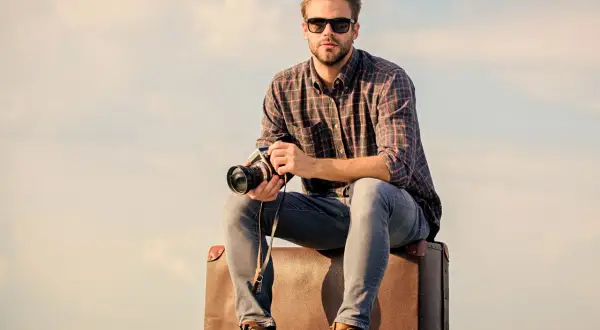 Joven viajero fotógrafo con cámara y maleta, listo para capturar el mundo.