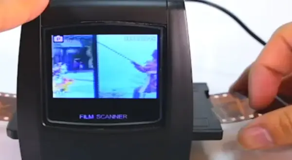 Un escáner de película digital muestra una imagen de un pescador. Se está introduciendo una tira de negativo en el dispositivo, mostrando cómo escanear negativos.