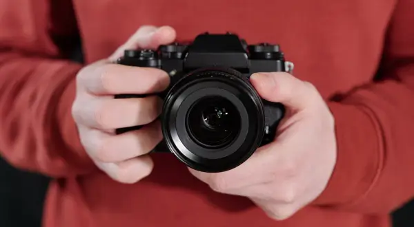 Manos sostienen una cámara negra, lista para el inicio fotografía.