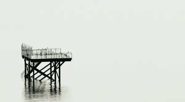 Plataforma solitaria sobre el agua, reflejo nítido. Fotografía minimalista que evoca calma y soledad.