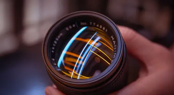 Primer plano de un objetivo de cámara vintage, reflejando luces de colores.