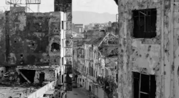 Calle devastada con edificios en ruinas, un cartel de "HOOVER" en lo alto. La mirada de Gabriele Basilico captura la desolación.