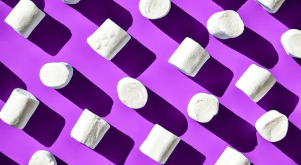 Malvaviscos blancos dispuestos en patrón diagonal sobre fondo morado, un ejemplo visual de la ley de pregnancia o buena forma.