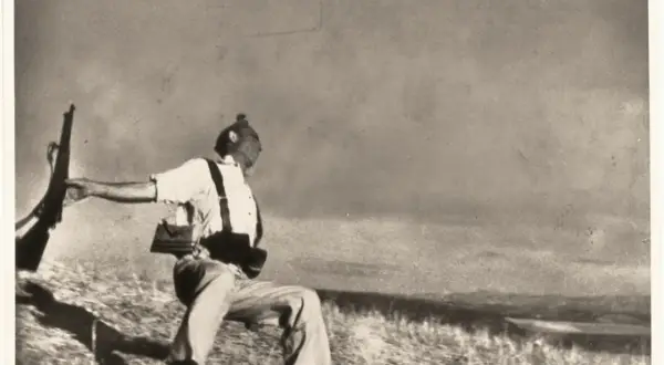 Soldado con rifle en mano, capturado en un momento dramático que evoca la muerte de Gerda Taro.