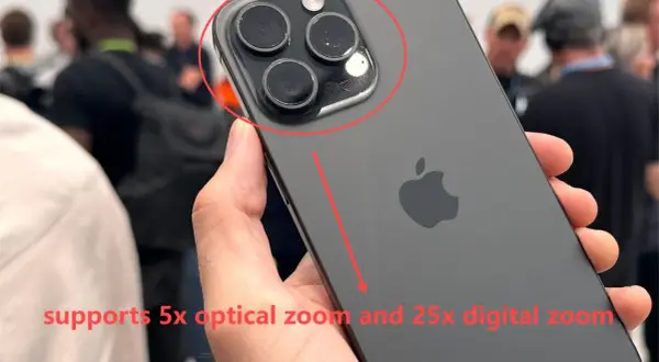 Mano sostiene un iPhone oscuro, mostrando su sistema de cámaras. El texto indica "zoom digital" de 25x y zoom óptico de 5x.