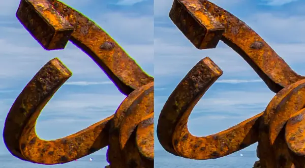 Escultura de metal oxidado con aberración cromática visible en los bordes, contra un cielo azul y mar.