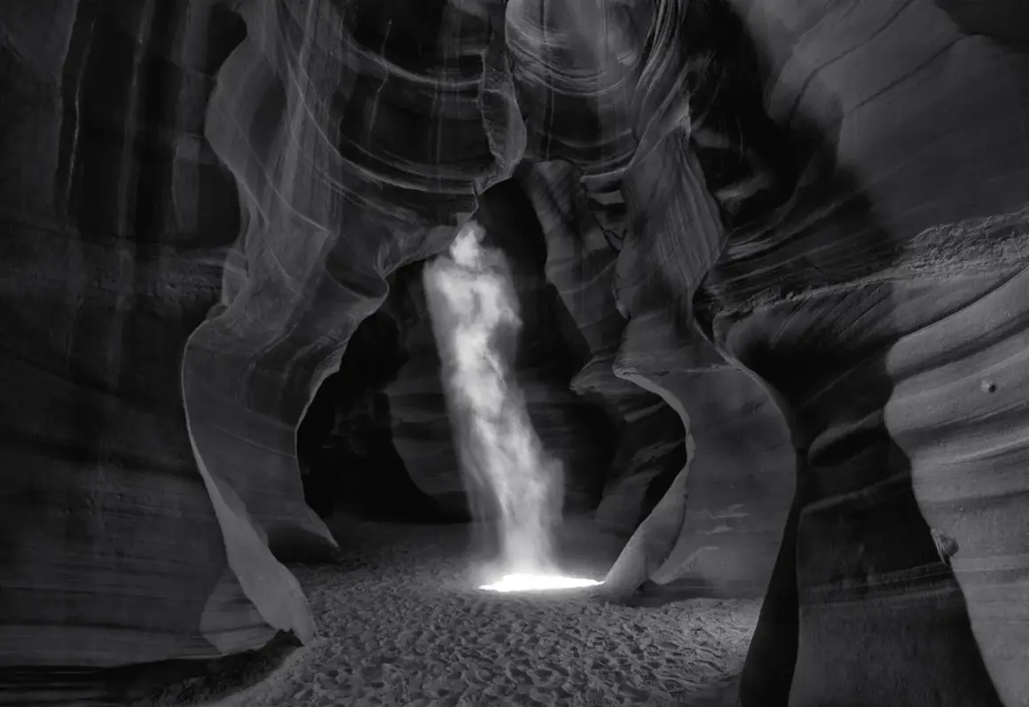 Columna de luz ilumina cañón de arena, creando una escena etérea. Esta podría ser la **fotografía más cara del mundo** por su belleza única.