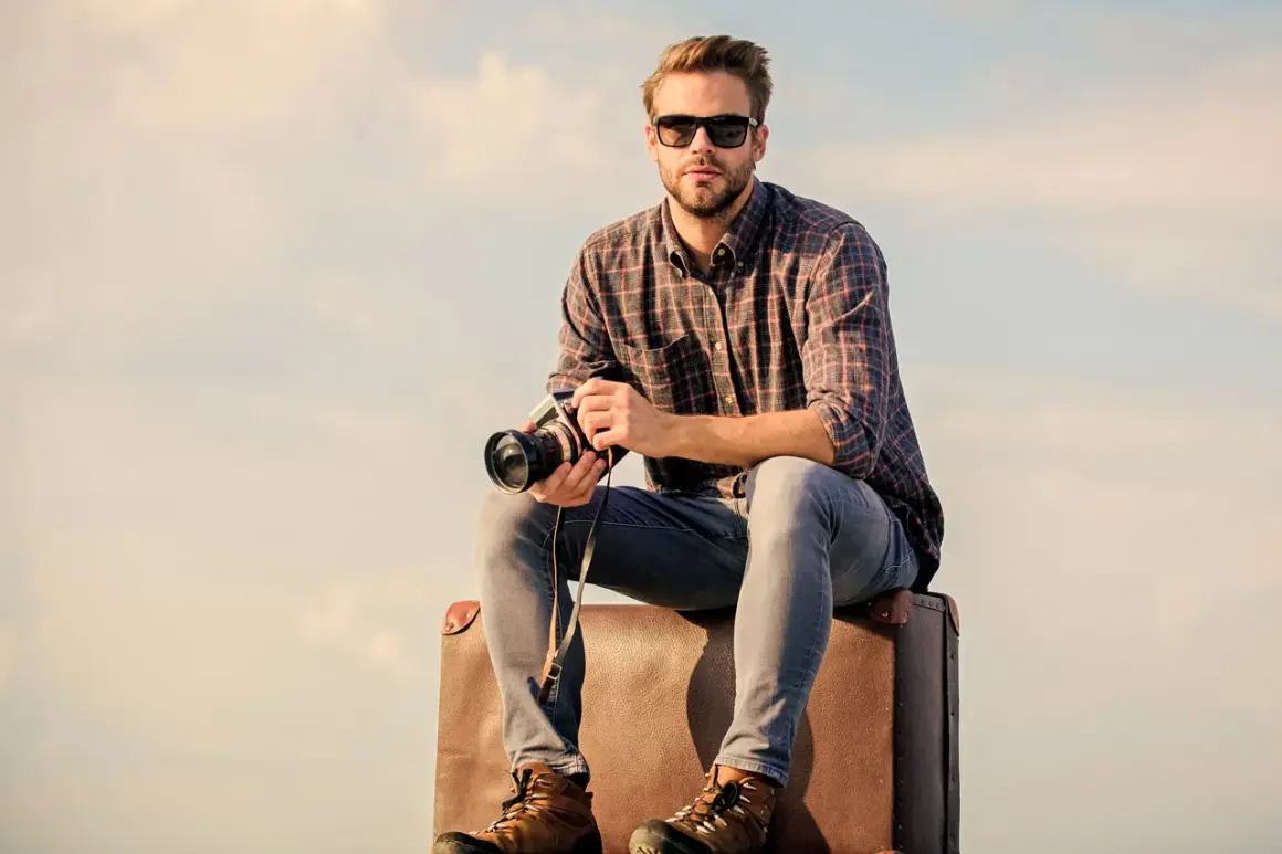 Joven viajero fotógrafo con cámara y maleta, listo para capturar el mundo.