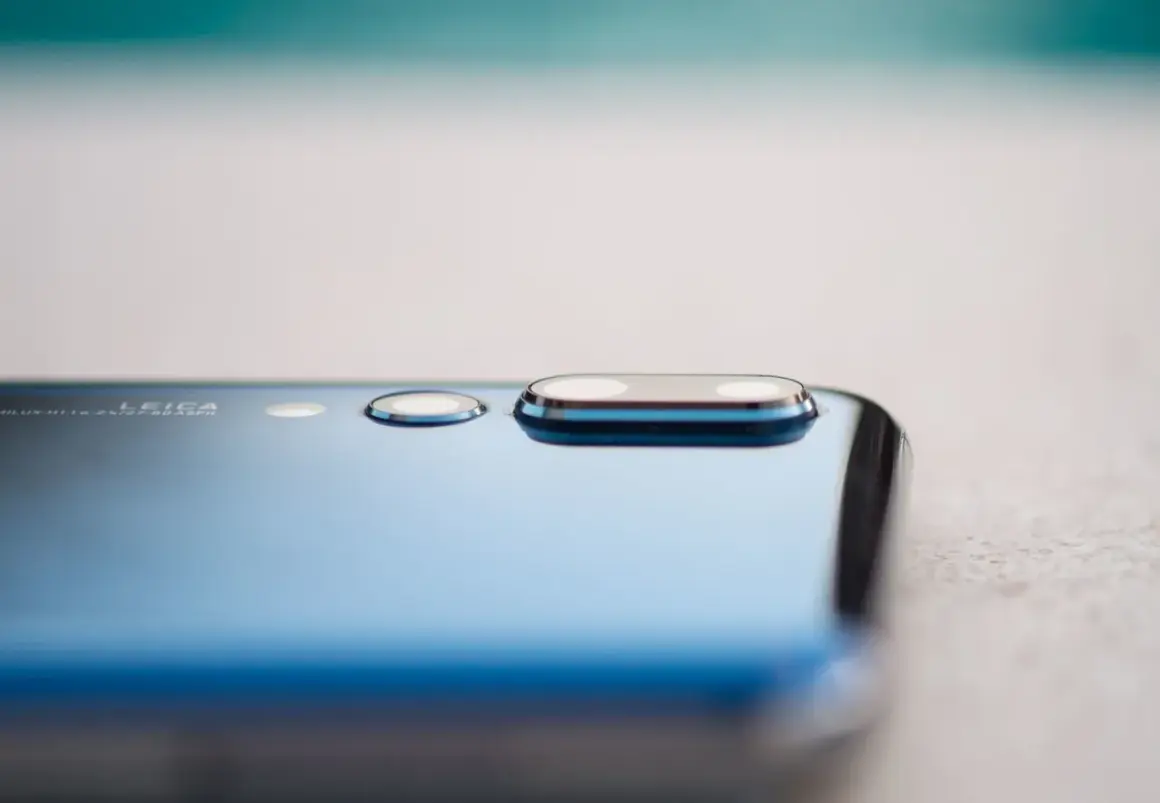Detalle de la cámara de un smartphone azul, mostrando el módulo de lentes Leica y la tecnología de pixel binning para capturar más luz.