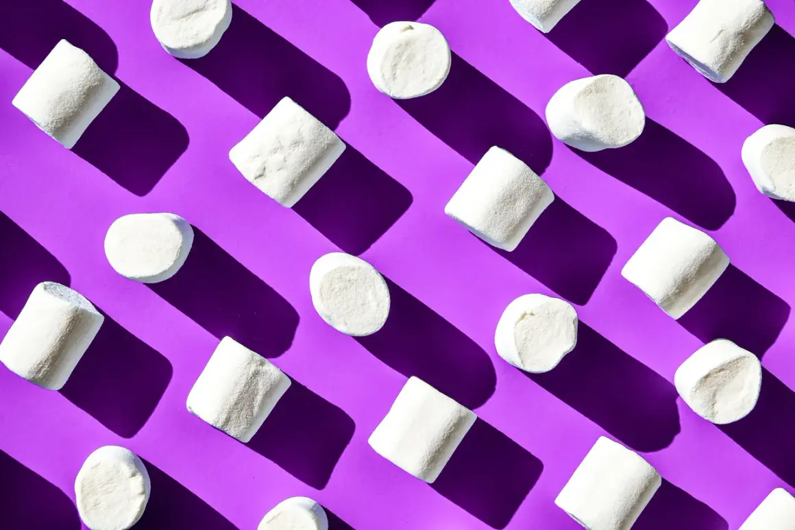 Malvaviscos blancos dispuestos en patrón diagonal sobre fondo morado, un ejemplo visual de la ley de pregnancia o buena forma.