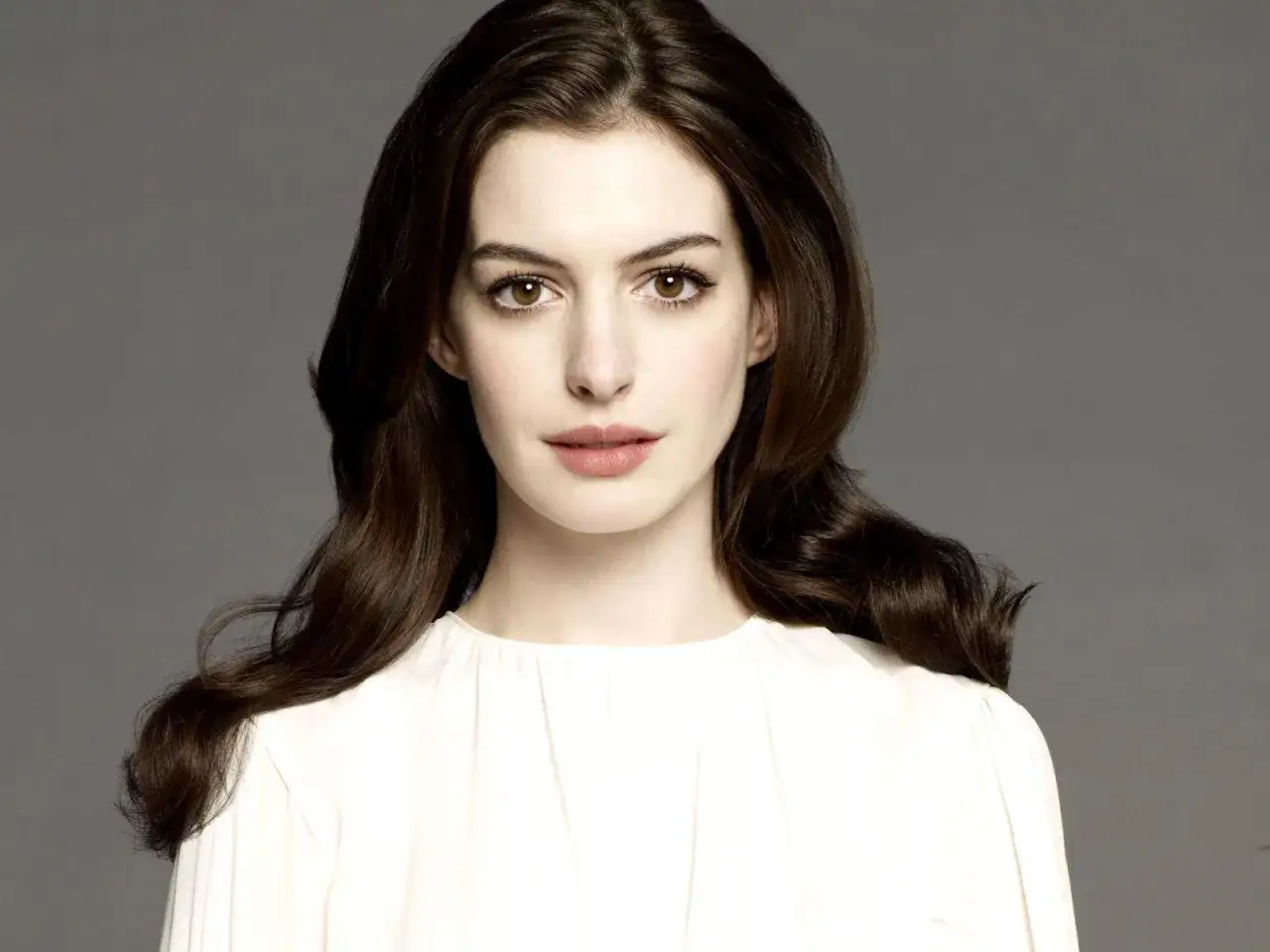 Plano medio corto de una mujer con cabello casta&ntilde;o oscuro y ojos marrones, vestida con una blusa blanca.