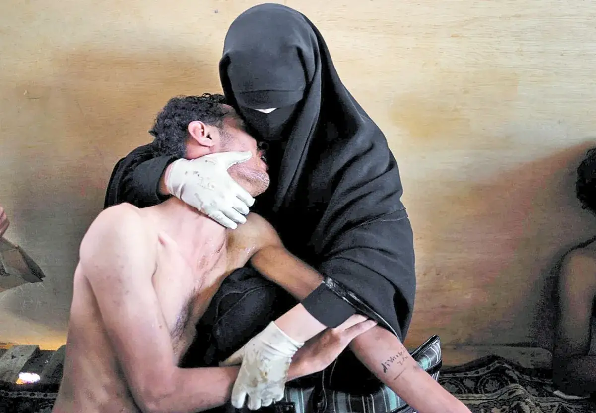 Una mujer con velo negro consuela a un hombre herido, capturado por Samuel Aranda en una imagen del World Press Photo.