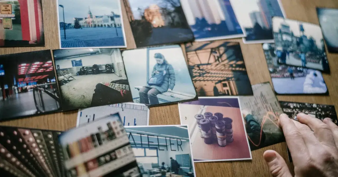 Un proyecto fotográfico en desarrollo. Varias instantáneas de escenas urbanas, personas y detalles, junto a rollos de película, sobre una mesa de madera.