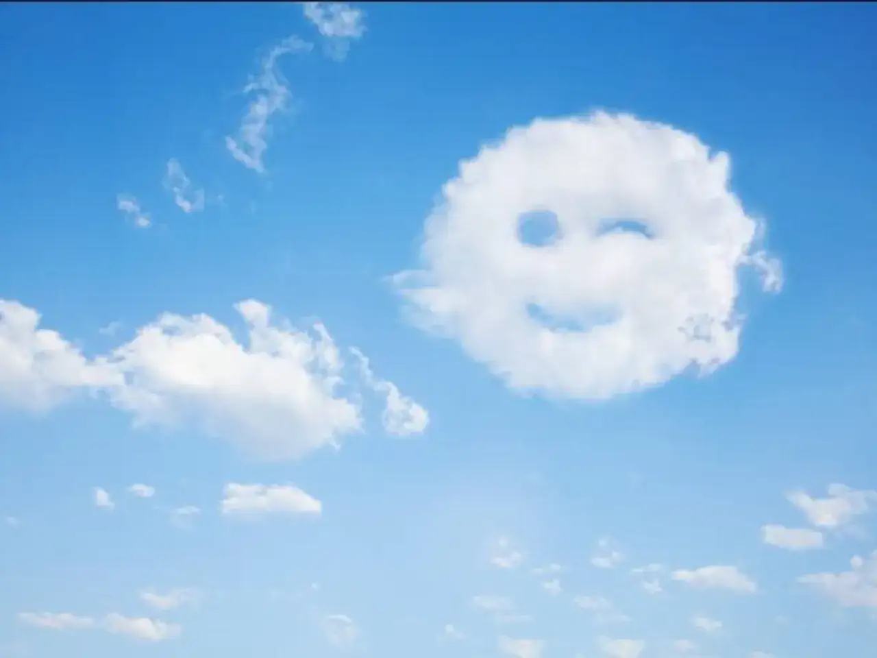 Nube con cara sonriente gui&ntilde;ando un ojo, un ejemplo de pareidolia en el cielo azul.