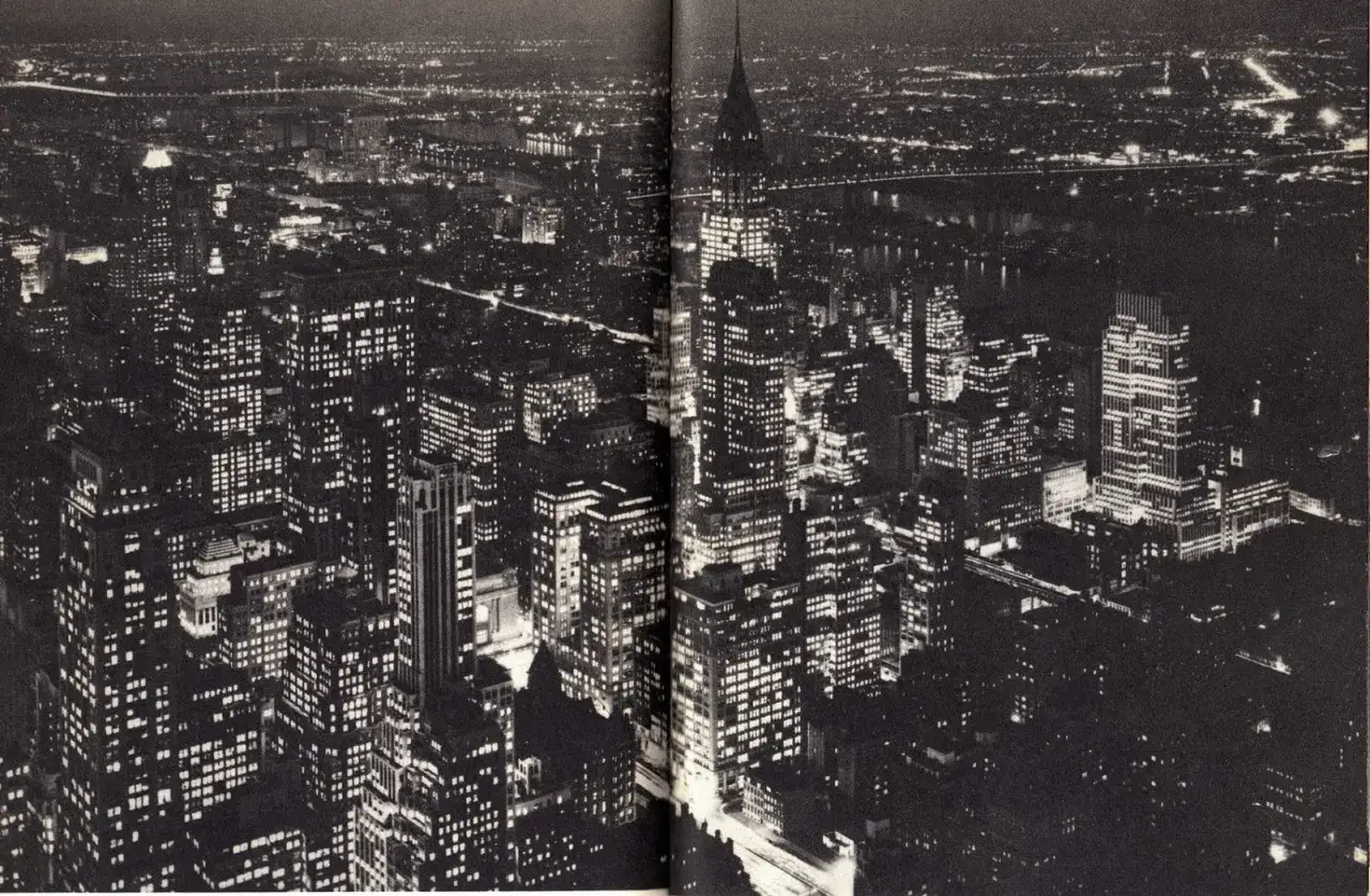 Vista nocturna de Nueva York, capturada por Andreas Feininger. Edificios iluminados se extienden hasta el horizonte.
